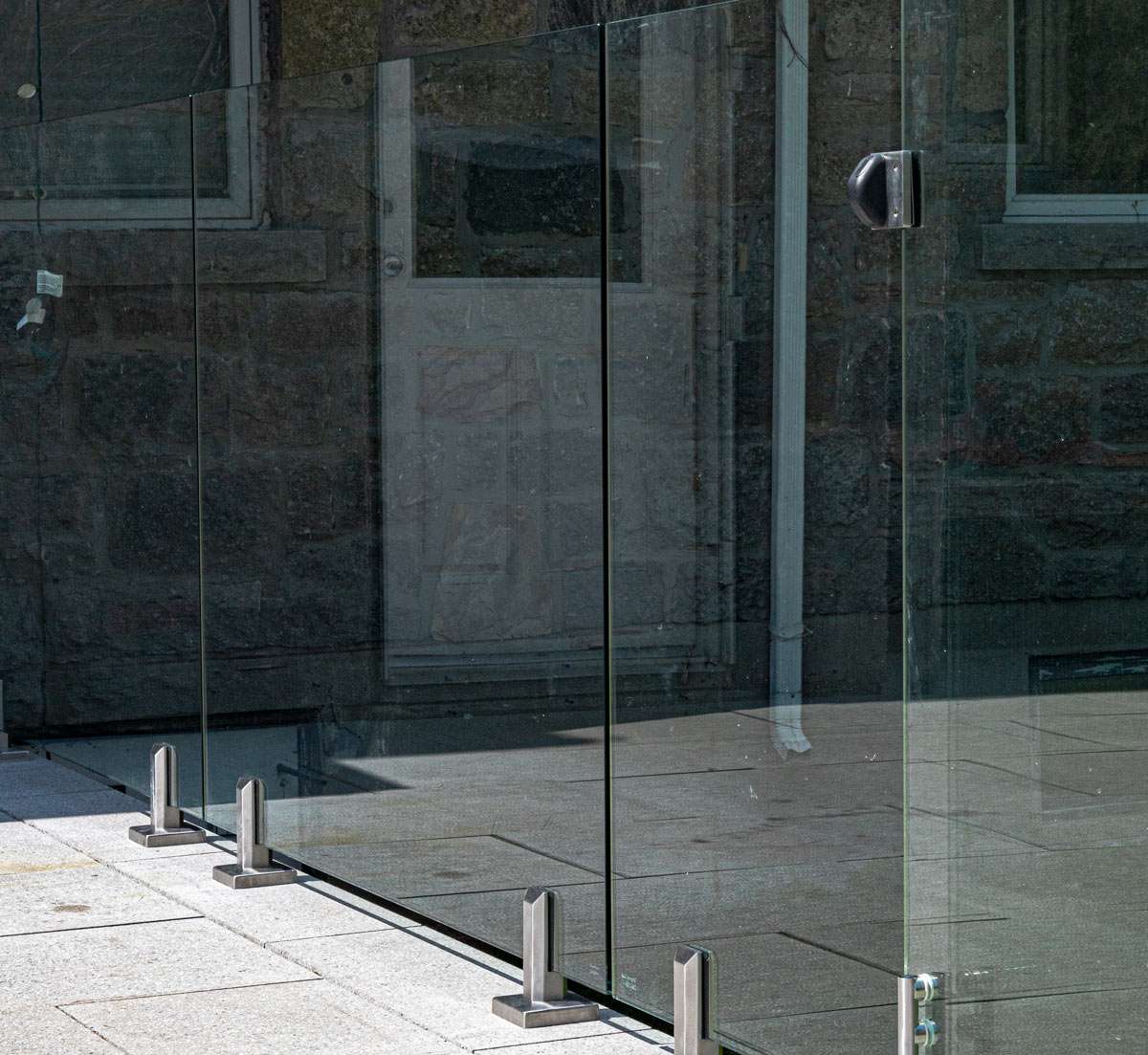 Glass railing spigots mounted on stone surface